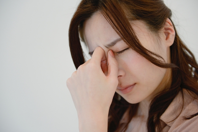 めまいで眉間に手を当てる女性