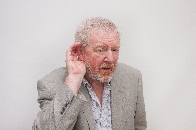 耳に手を当て聞き返す老人